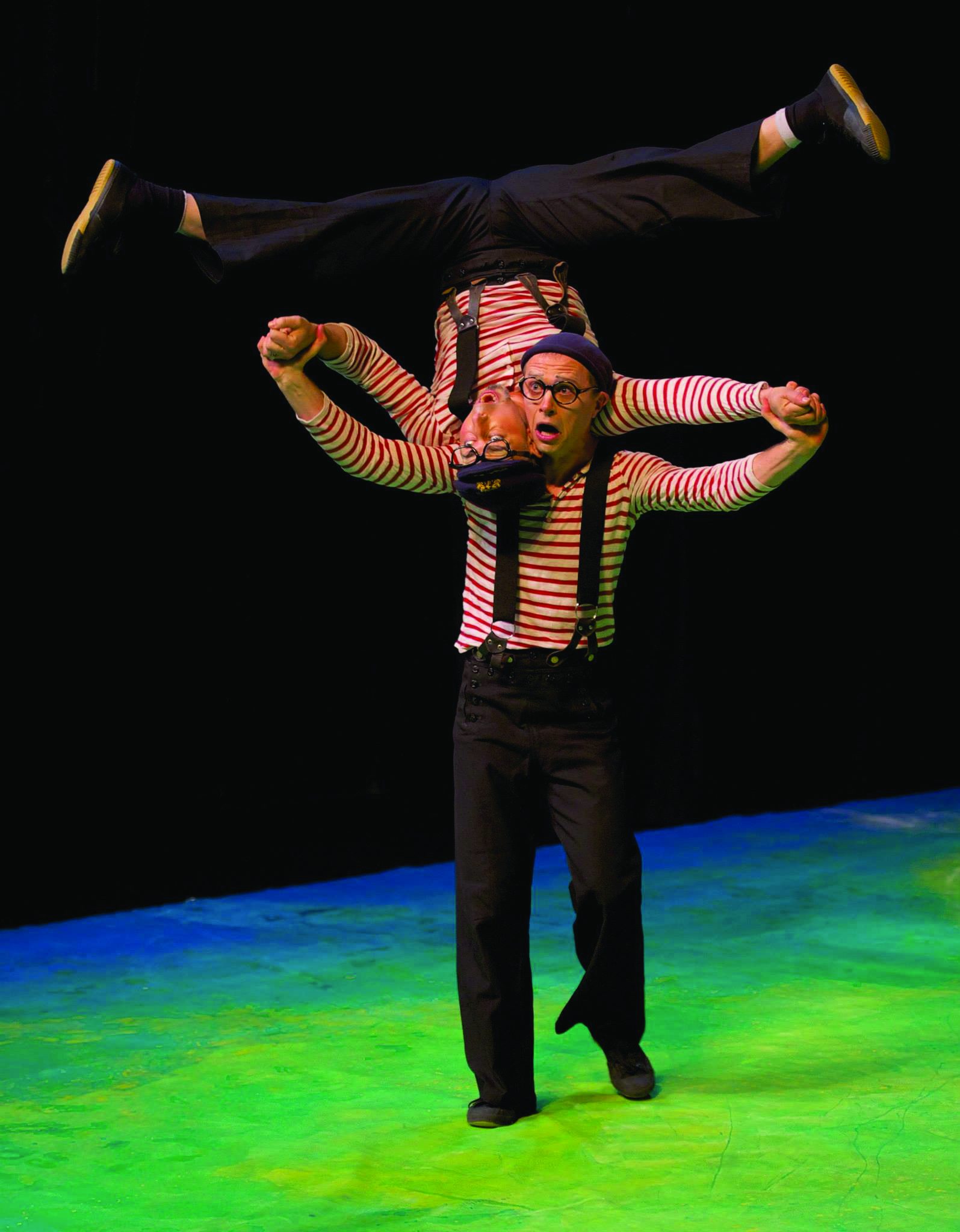 A performer balancing upside down in a straddle on his partner's shoulders